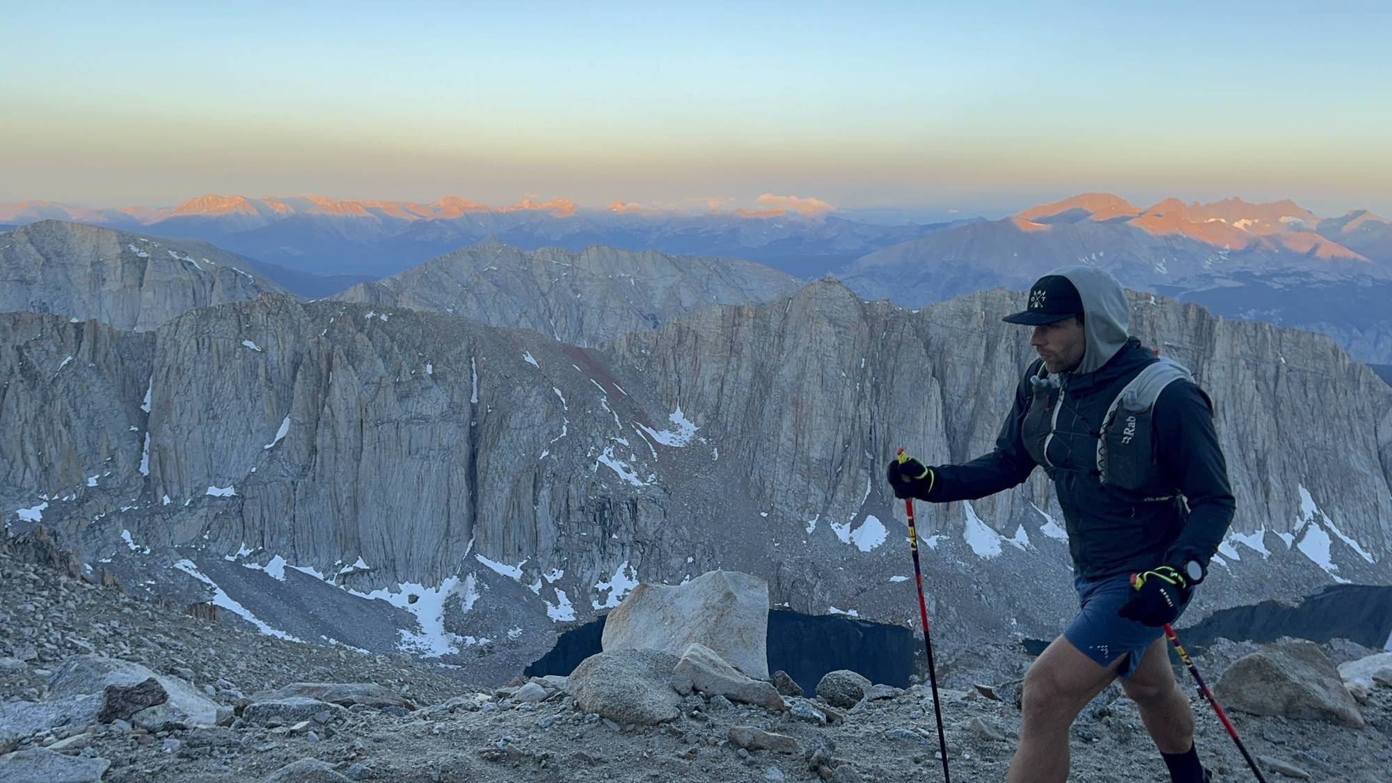 Hiker on the Mount Whitney Trail at dawn with alpenglow on the Sierra Nevada