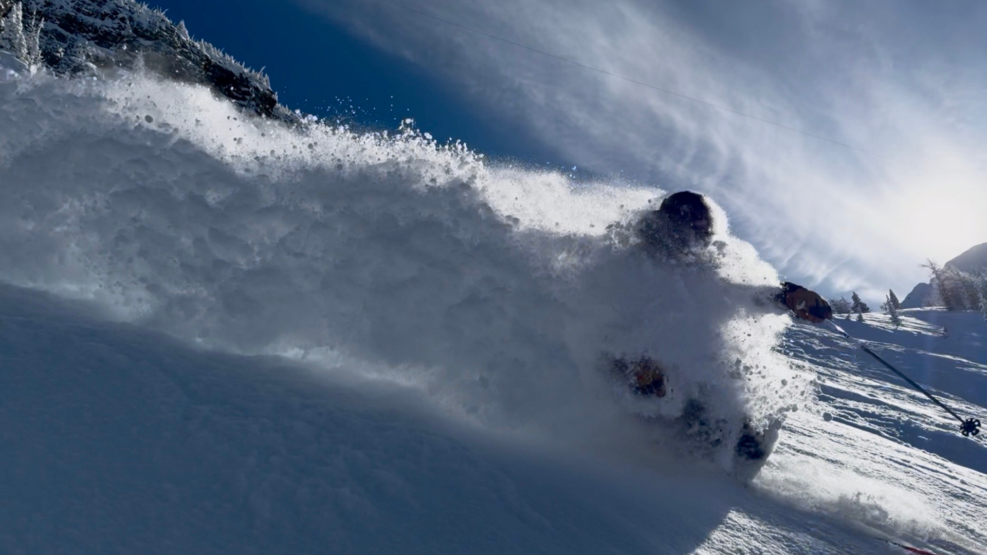 Skier making a deep powder turn with a face shot