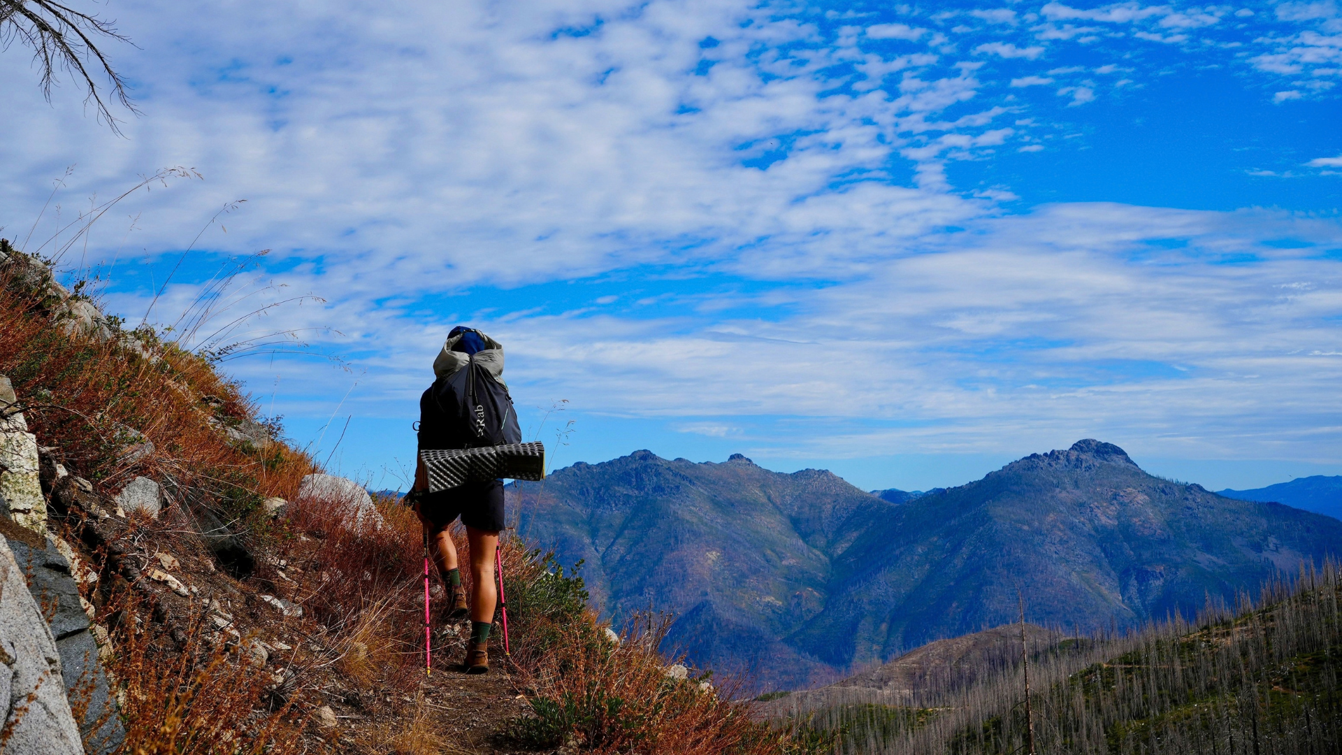 Hiker high on a ridge with an epic mountain backdrop