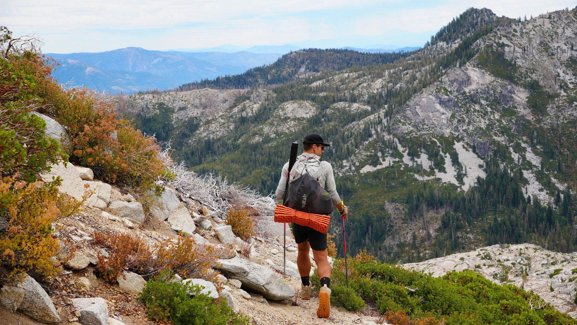 Hiker descending steep terrain with trekking poles