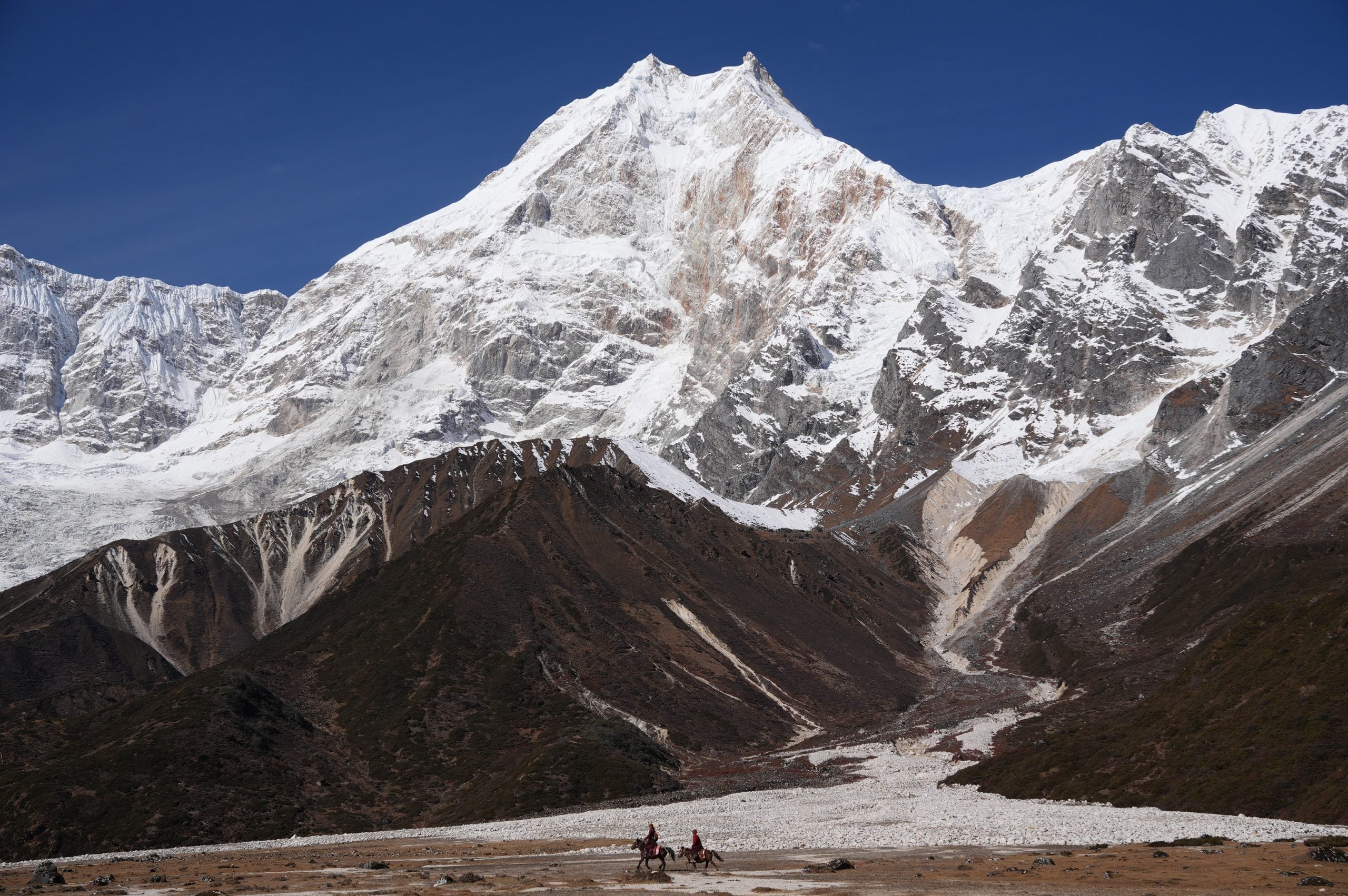 Two monks on horseback with Manaslu up close